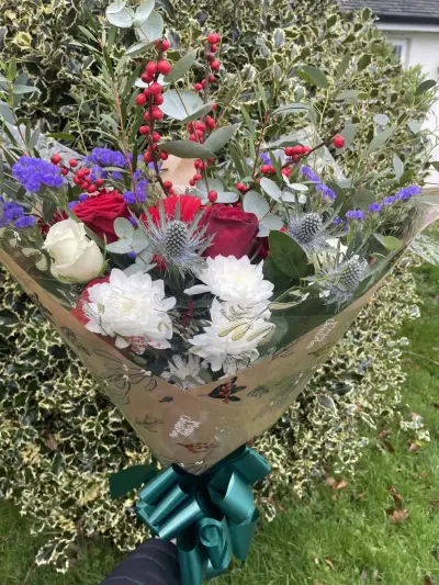 A wrapped bouquet with eryngium and red roses
